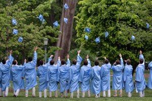 UNC students dressed in Carolina blue, toss their graduation caps.